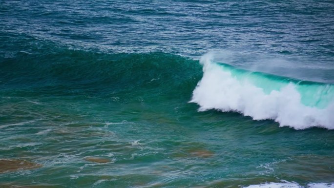 蓝绿色的海浪在慢动作中膨胀。泡沫强大的桶滚