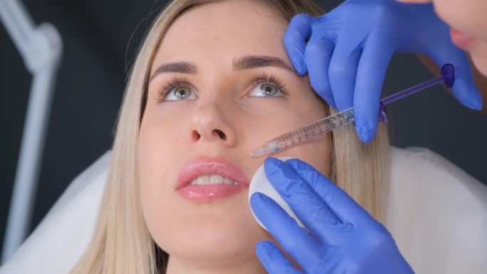 美容师给女性脸上注射肉毒杆菌来减少皱纹。