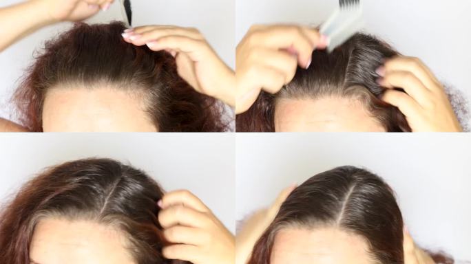 特写:一个无法辨认的女人用鼠尾梳把深棕色的卷发分开，露出头发的根，灰白的头发。