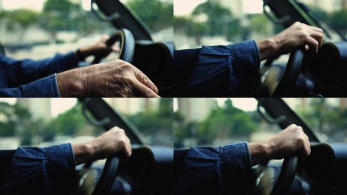 近距离手握方向盘驾驶在城市。一名年长的白人男性司机在行驶的车辆里打转弯信号
