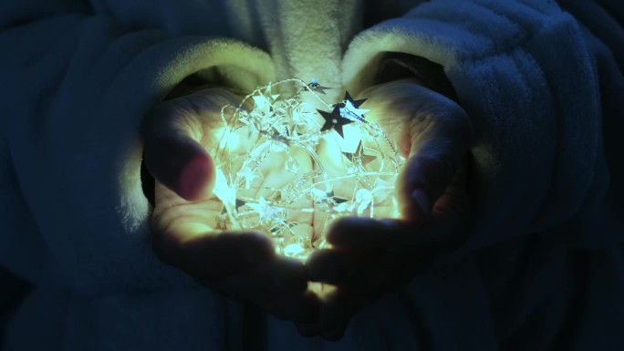 女人的手握和保护灯泡在黑暗中点亮的特写。希望和浪漫的概念。做白日梦的人做白日梦的人的生活方式。节日圣