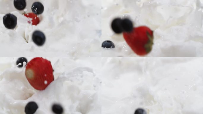 慢镜头:新鲜浆果落入奶油中。特写多汁甜覆盆子蓝莓黑莓草莓落入牛奶