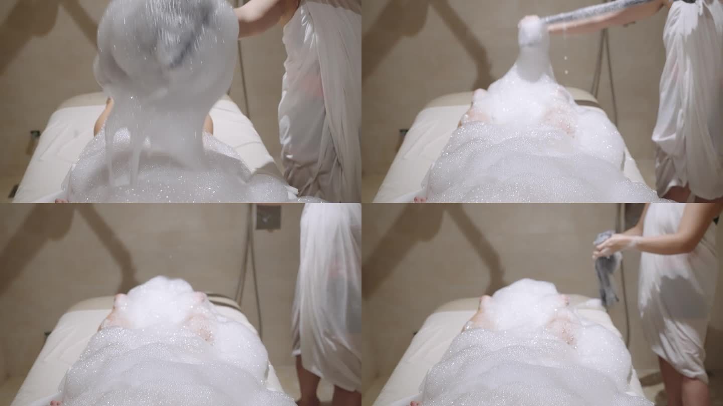 在土耳其浴室里，水疗中心的工作人员在泡沫肥皂泡沫下用水流给女人洗澡。女性放松，接受身体皮肤治疗、清洁