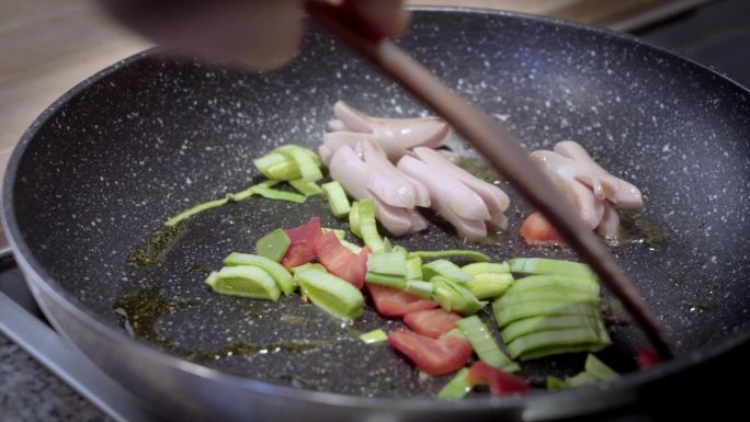 用香肠煎锅。把蔬菜倒进锅里。辣椒粉和韭菜。慢动作视频。准备食物。