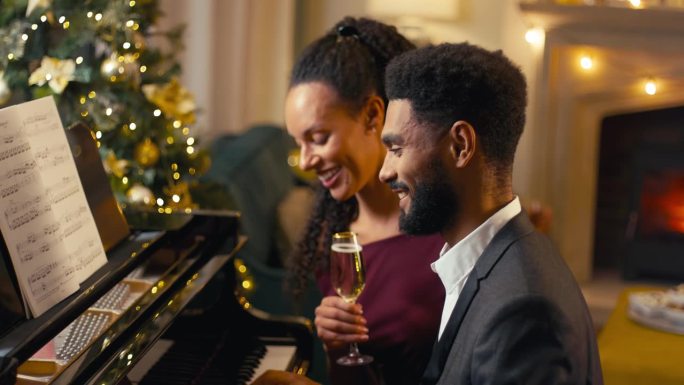 夫妇围坐钢琴边唱边弹，一起庆祝圣诞或新年