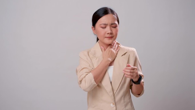 一位亚洲妇女喉咙痛，孤立地站在白色背景上。