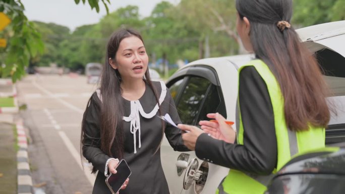 亚洲女司机与年轻女车险官员谈话同意的意外索赔将被评估和处理。