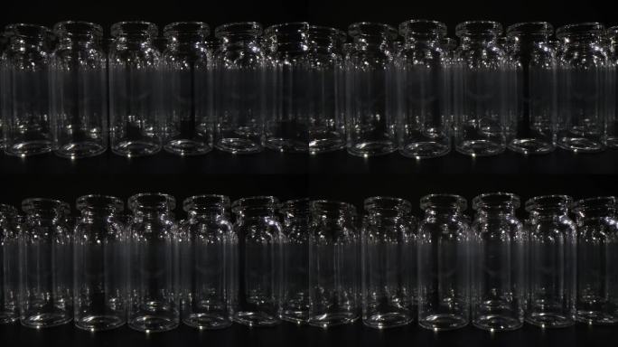 黑色背景上一排排装疫苗和药品的空玻璃瓶