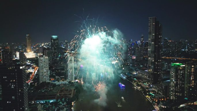 多色烟花在城市和摩天大楼上表演，庆祝夜晚的灯光、河流和曼谷大桥