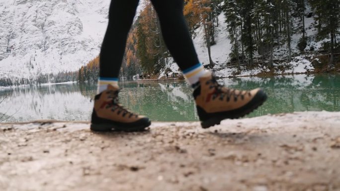 穿鞋女游客在白云岩湖和雪山森林中行走的低剖面