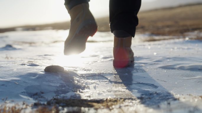 青海湖边人迎着阳光走在破碎的冰面
