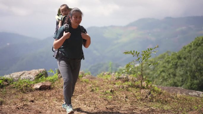 母亲带着儿子背着儿童背包在山上徒步旅行