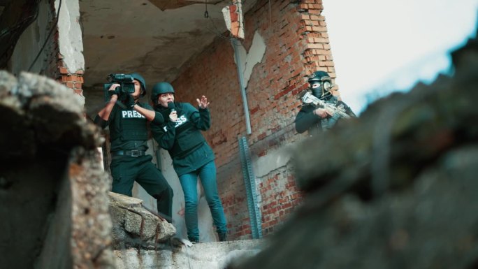 战地女记者拿着麦克风报道新闻，摄影师在战区一座被炸毁的建筑现场拍摄新闻更新