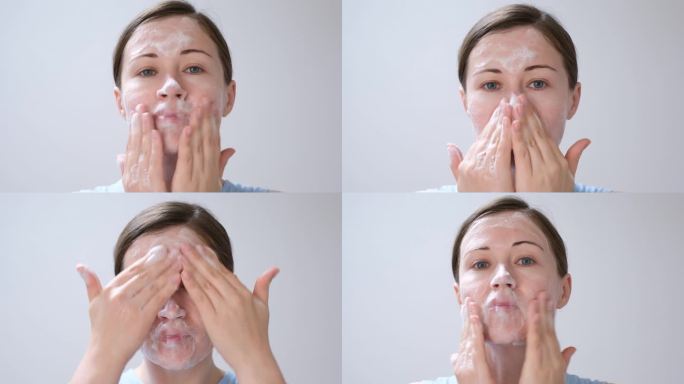 一名年轻女子将洁面泡沫涂抹在脸上(特写，白色背景)。