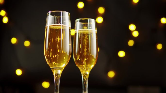 金色香槟酒杯特写，气泡酒。酒精黄金饮料黑色背景与灯光，庆祝，节日。