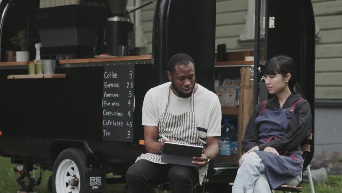 两个咖啡拖车的咖啡师，一起使用数码平板电脑