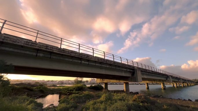 迷人的延时拍摄序列，不断变化的云舞在混凝土桥的坚固背景下展开，优雅地横跨整个场景。