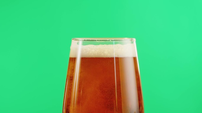 泡沫啤酒在玻璃特写。酒精金色啤酒杯喝。清新的淡啤酒在绿色色度键背景。
