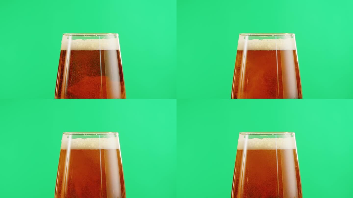 泡沫啤酒在玻璃特写。酒精金色啤酒杯喝。清新的淡啤酒在绿色色度键背景。