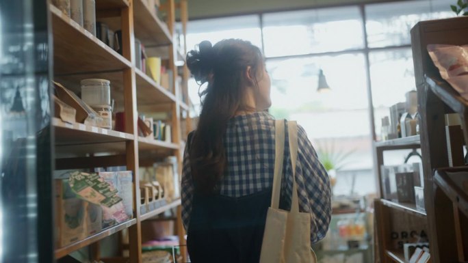 年轻的亚洲妇女在环保商店购买食品的背影。