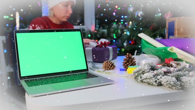 笔记本电脑与空白的绿色屏幕躺在桌子上的女孩包装礼盒系蝴蝶结与丝带
