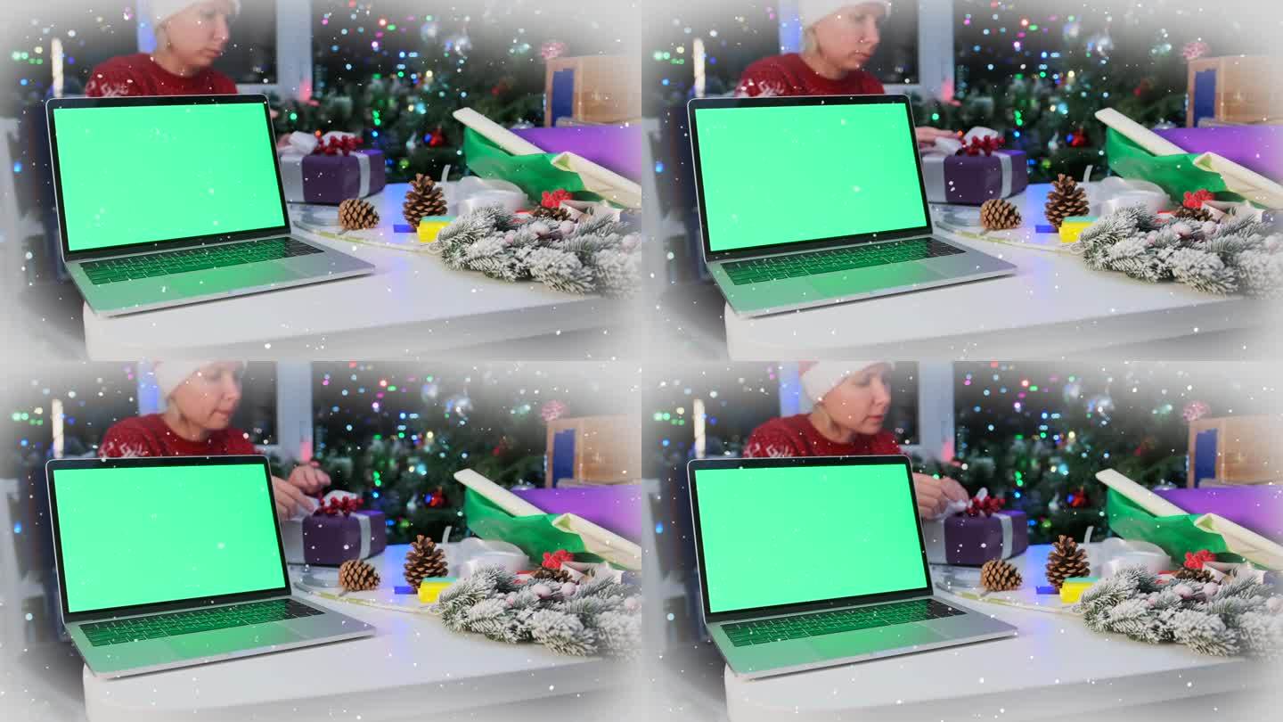 笔记本电脑与空白的绿色屏幕躺在桌子上的女孩包装礼盒系蝴蝶结与丝带