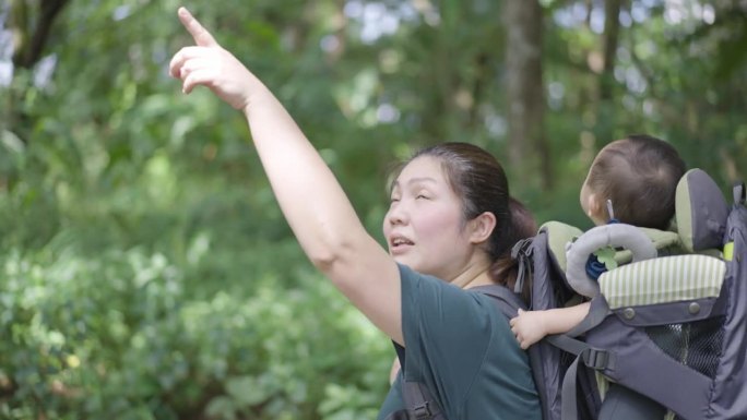 母亲带着儿子背着儿童背包在山上徒步旅行