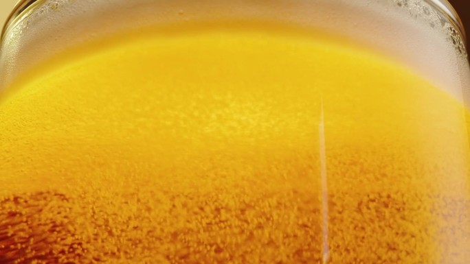 泡沫啤酒在玻璃特写纹理。酒精金色啤酒杯喝。新鲜的淡色麦酒。