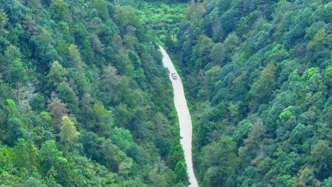 航拍新能源汽车行驶在森林山路上行驶