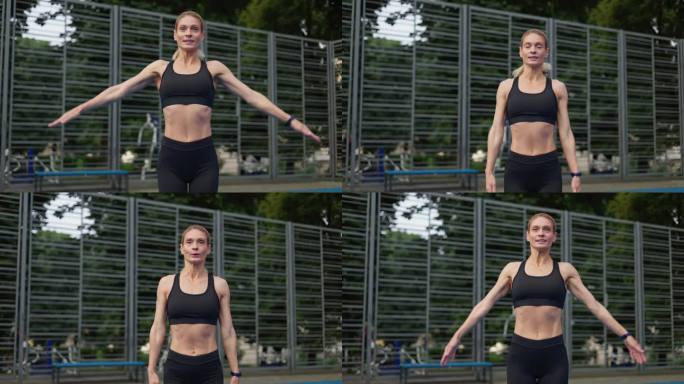 在户外锻炼时，微笑的健康女子正在进行跳jack运动。精力充沛的女士穿着运动服，改善心血管健康，促进新