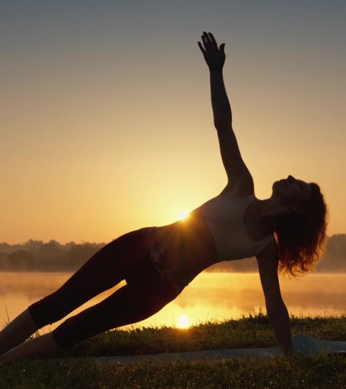 与自然和谐的瑜伽:健康生活方式的秘密。一名妇女在自然环境中将冥想融入瑜伽练习中。剪影男子在日出，锻炼
