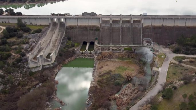西班牙瓦伦西亚省用于灌溉和蓄水的Bellús重力坝前面的全景无人机视频，安全阀满负荷运行