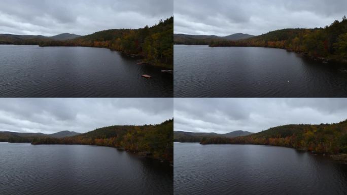 雨前，郁郁寡欢的鸟瞰图在色彩斑斓的秋天森林山坡附近的黑暗湖泊