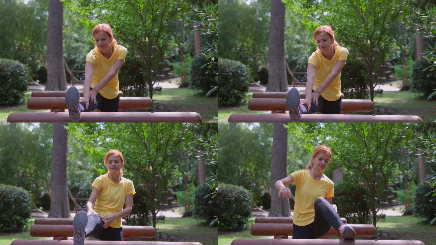 健康的中年成年妇女在自然公园的木栏上伸展双腿