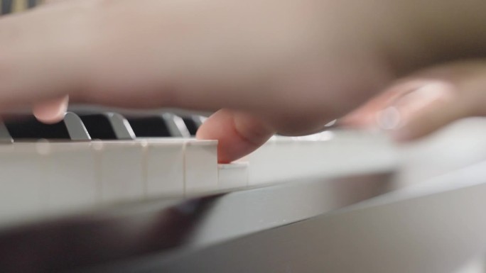 人类手指在钢琴键盘上弹奏音乐的极端特写。