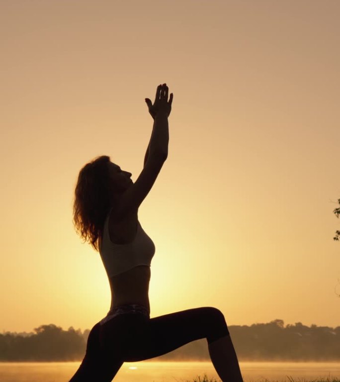 瑜伽是实现身体和精神和谐的工具。一个女人在自然环境中发现了瑜伽的魔力。日出时的自我提升和身心发展垂直