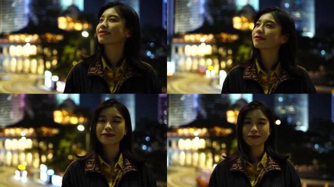 香港街头夜晚面对镜头微笑的女性青年开心笑