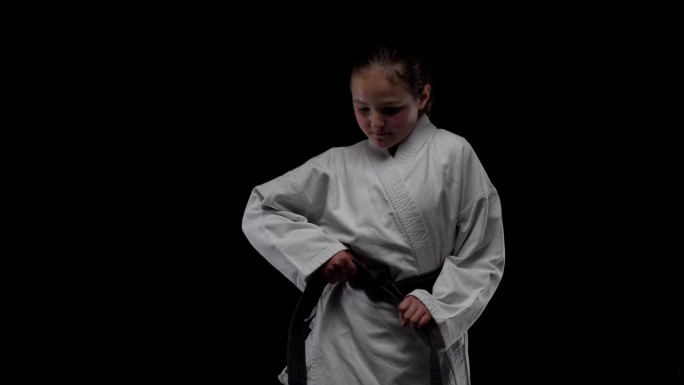 身穿和服的年轻女孩在黑色背景下练习空手道