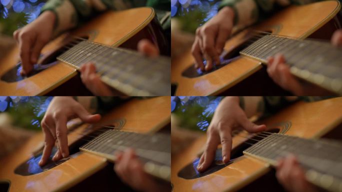 吉他顶部的特写，一个男孩的手在拨动琴弦。