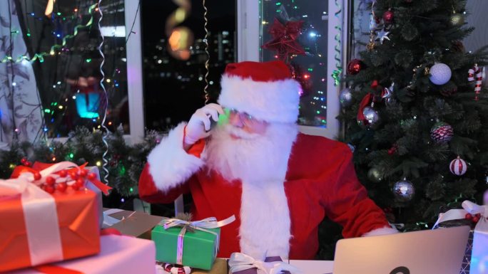 圣诞老人一边唱圣诞歌，一边用智能手机聊天，一边跳舞，坐在他的工作室里