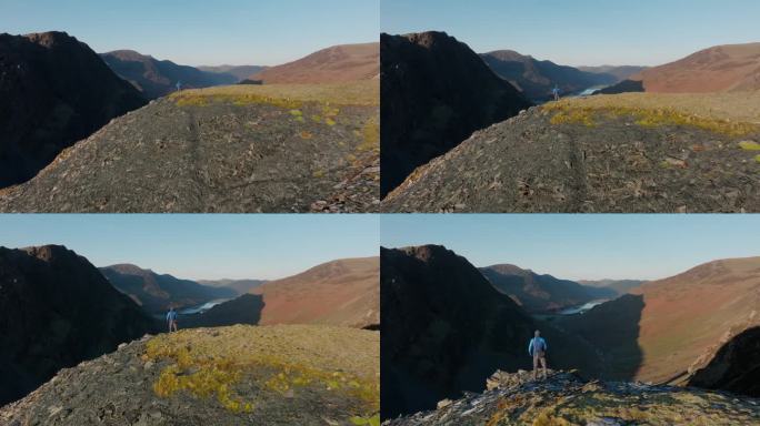 山行者站在悬崖边，朝崖边飞过去，在清晨秋日的阳光下，显露出山谷的阴影。英国坎布里亚郡英格兰湖区的Ho
