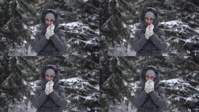 大雪中，一位年轻女子站在冷杉树的背景下，用手揉搓着御寒。一个女孩戴着眼镜，穿着带兜帽的羽绒服，站在那