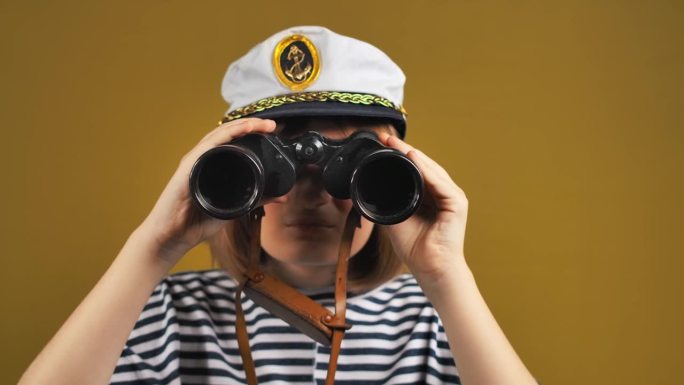 一个戴着水手帽的兴高采烈的少女正通过双筒望远镜观看