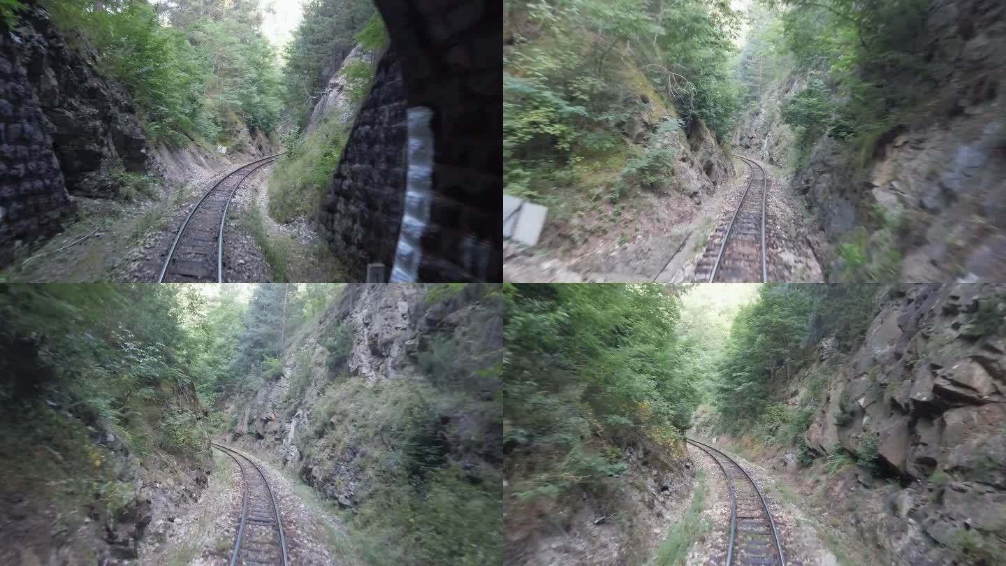 火车在隧道出口处行驶时，山间的复古铁轨