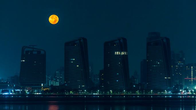深夜的城市月亮悄悄穿过高楼建筑天际线