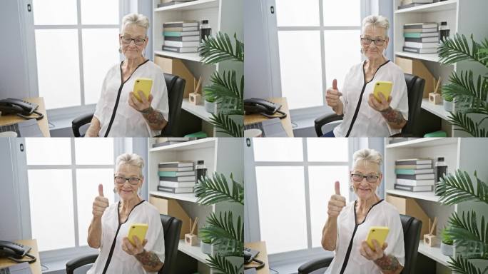 开朗、头发花白的资深商业女性在办公室使用智能手机时竖起大拇指向成功致敬，体现了积极、成功、成熟的老板