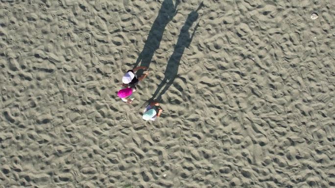 无人机拍摄的画面显示，三个戴着棒球帽的孩子在沙滩上投下长长的影子