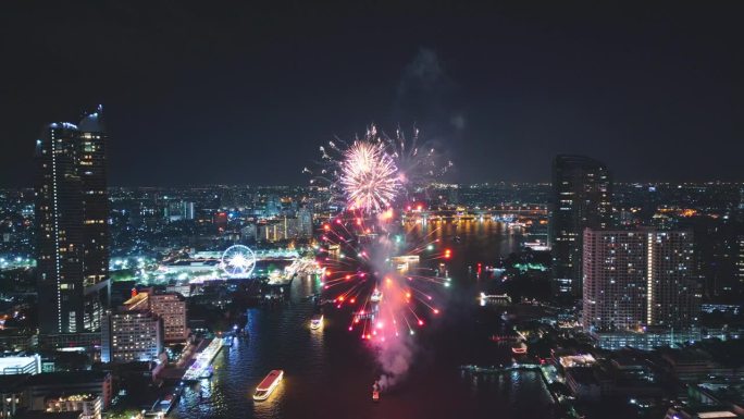 多色烟花在城市和摩天大楼上表演，庆祝夜晚的灯光、河流和曼谷大桥