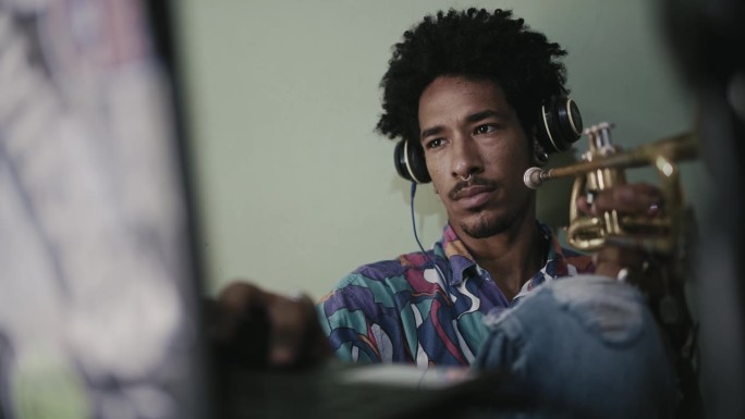 时髦的非洲裔美国人用笔记本电脑录制歌曲——年轻的音乐制作人用小号