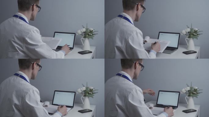 年轻的男医生戴着眼镜，穿着白大褂，坐在办公桌前操作笔记本电脑。医生检查病人的化验结果并将数据输入电脑